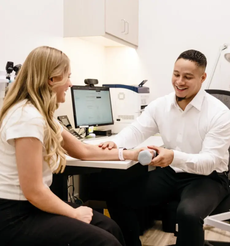 Male practitioner smiles while helping a female patient during a physical therapy session (1)